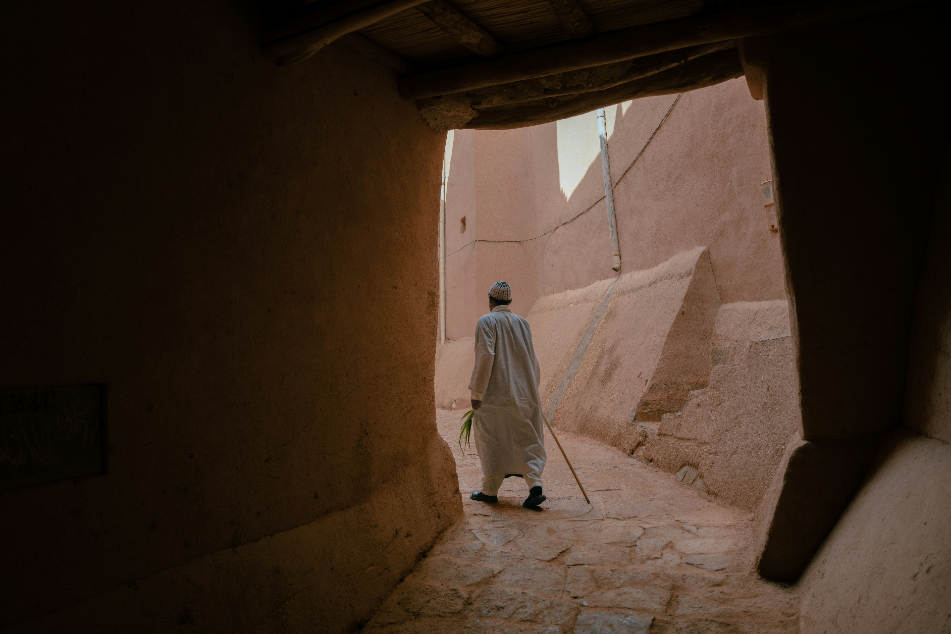 Homme en djellaba blanche dans une ruelle de terre ocre