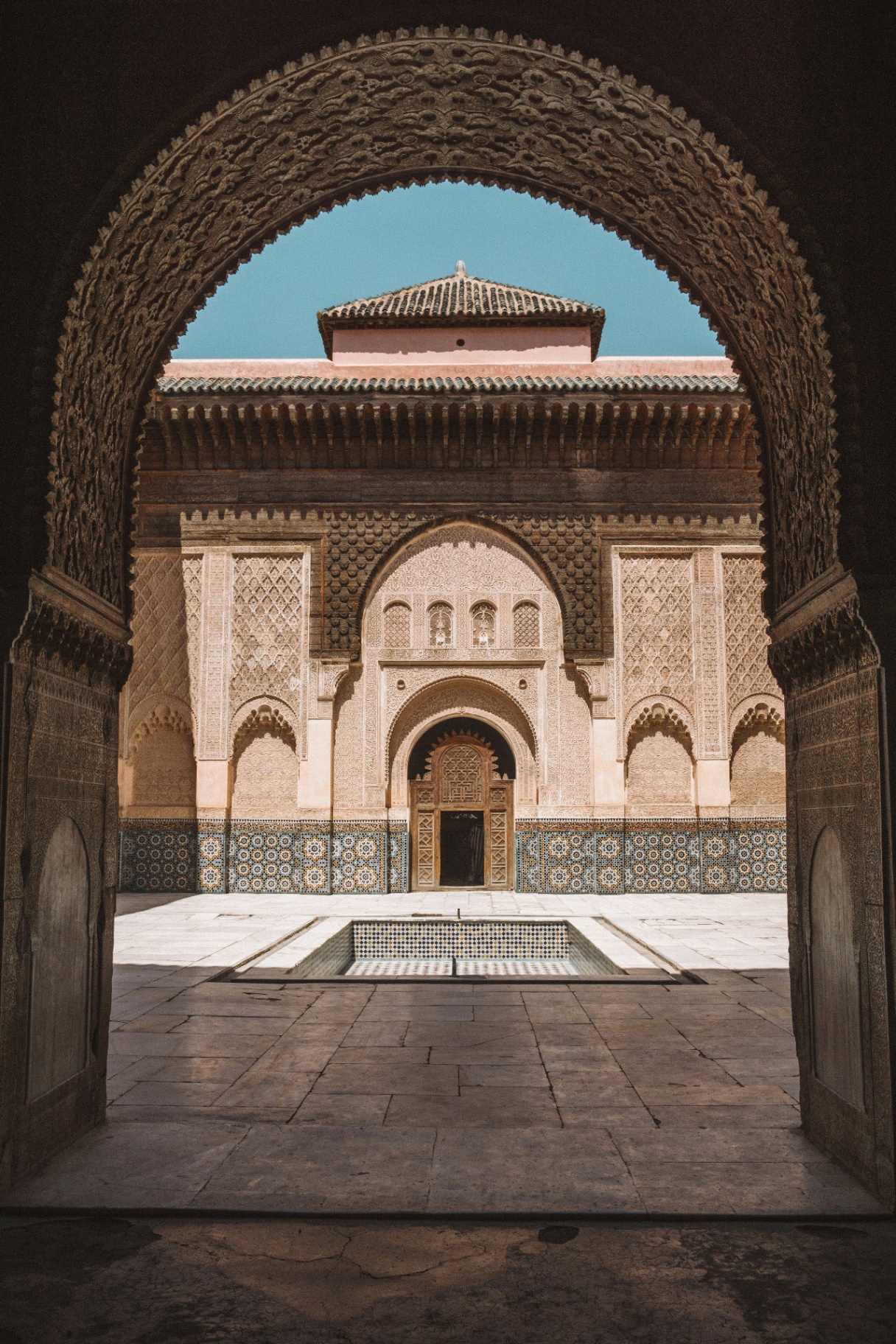Cour intérieure d'une medersa marocaine vue depuis une arche sculptée