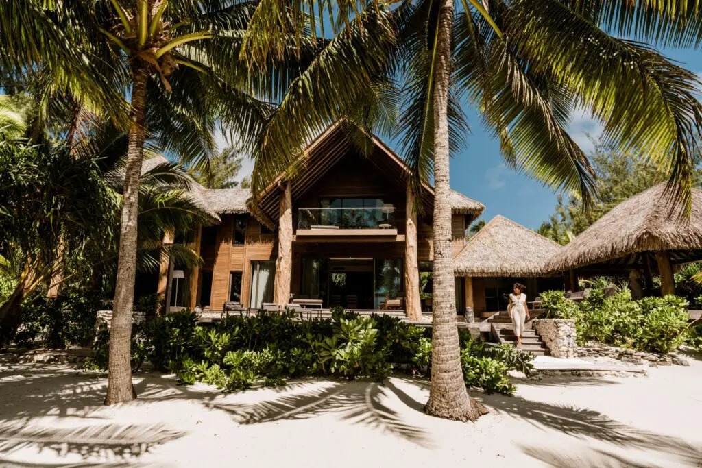 Façade en bois d'une villa de The Brando entourée de cocotiers
